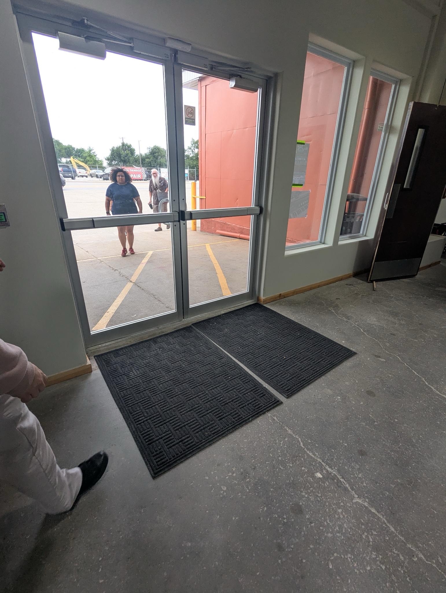 A photo of the Clover24 front doors from the inside, with an individual standing on the other side of the glass doors
