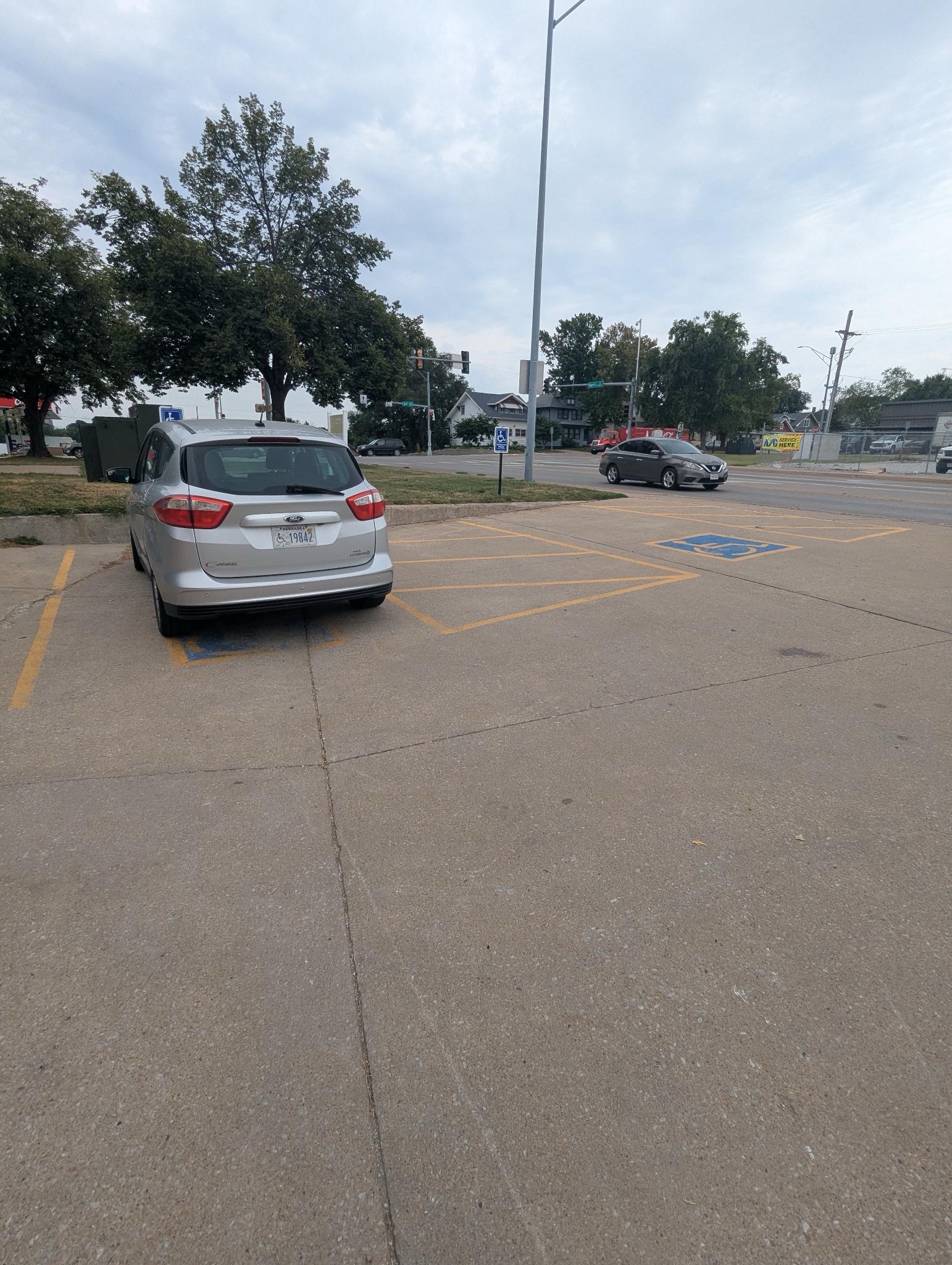 A photo of a grey minivan in one of the Clover 24 parking lot's handicap spaces