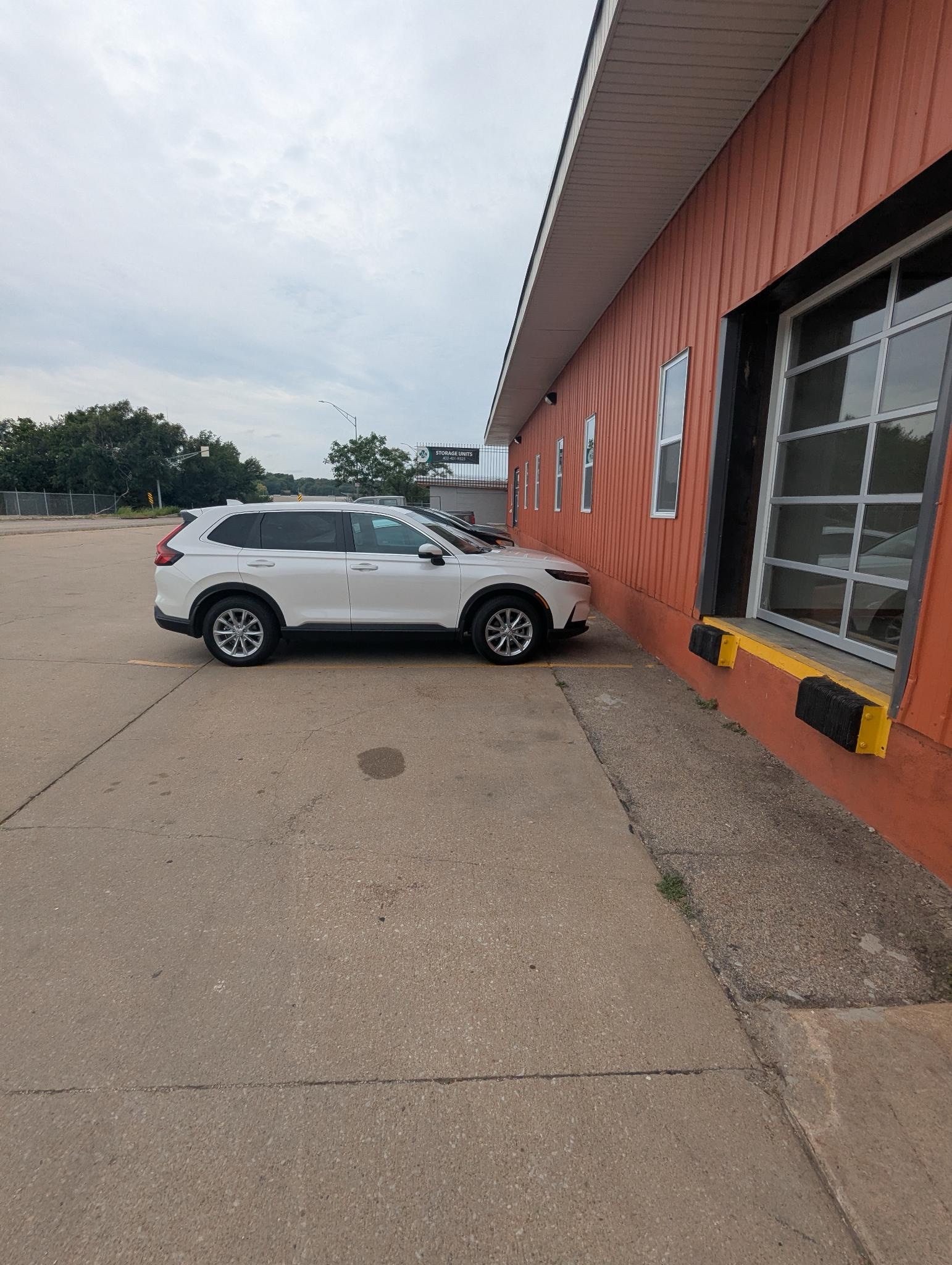 A photo of a white car in front of the Clover 24 building