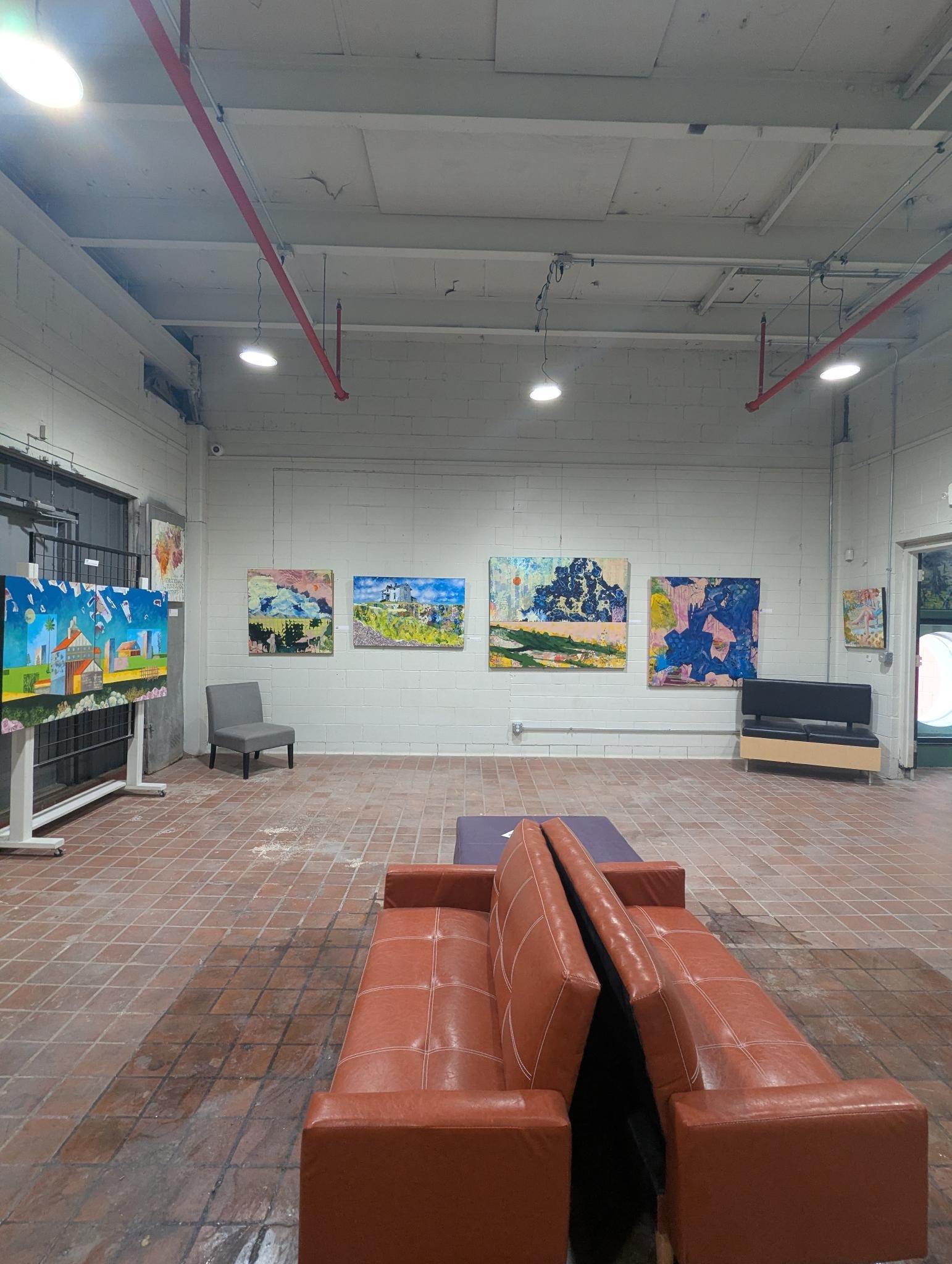 A photo showing couches and an armchair in the Clover24 gallery. Pieces of art line the walls